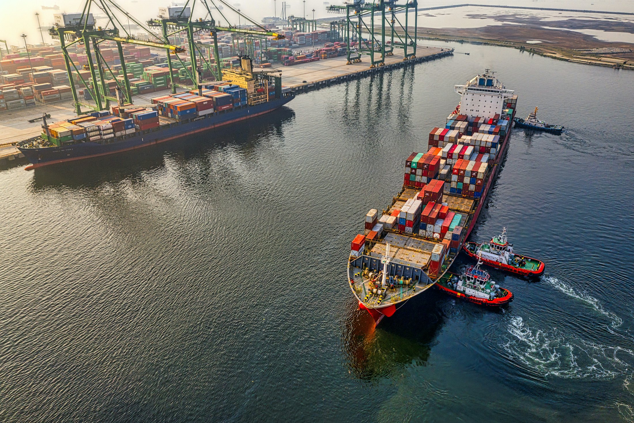 Aerial view of container ships and tugboats working in a port